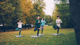 Four people doing yoga tree pose in park