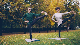 Two women practicing yoga in a park.