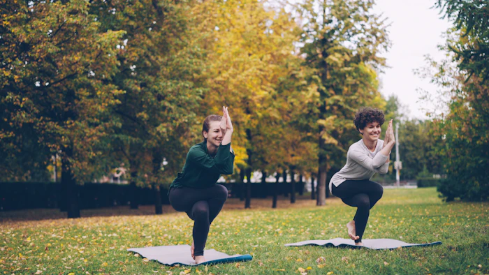 Two women doing yoga in a park