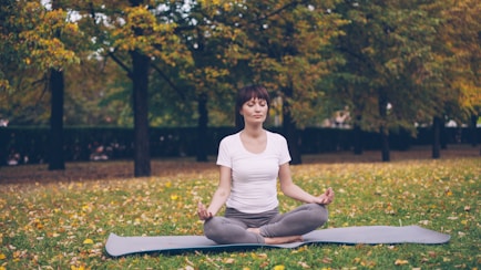 Woman meditating in a park during autumn.