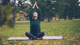 Woman meditating in a park with arms raised