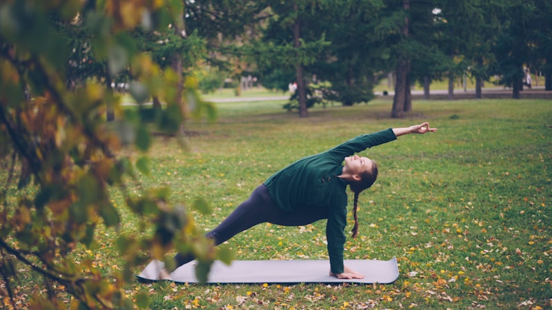 Woman practicing yoga on a mat in a park — choosing the right mat for senior flexibility and joint comfort