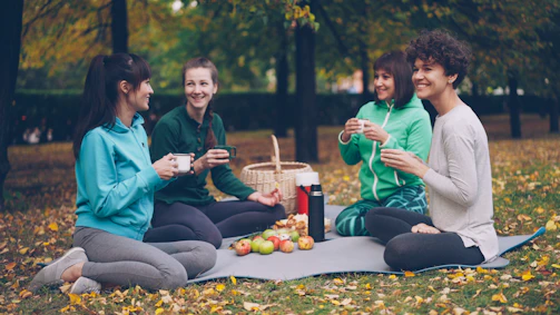 Four friends enjoying a picnic in an autumn park.