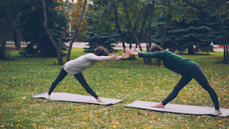 Two people doing yoga in a park.