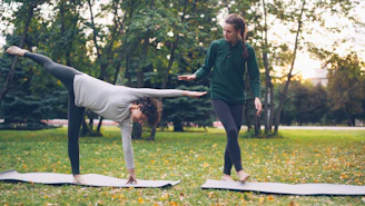 Two women practicing yoga in a park