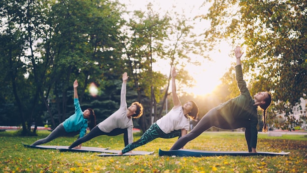 People practicing yoga in a park at sunset