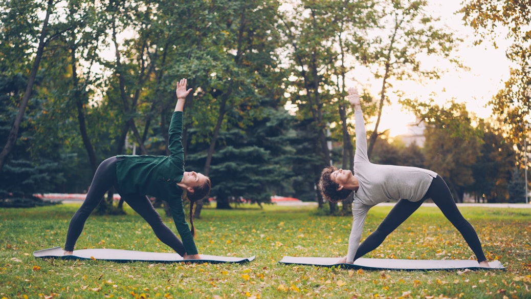 Two women doing yoga in a park.