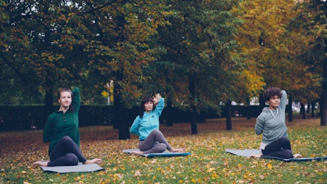Three women practicing yoga outdoors in autumn