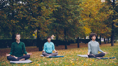 Three people meditating in a park