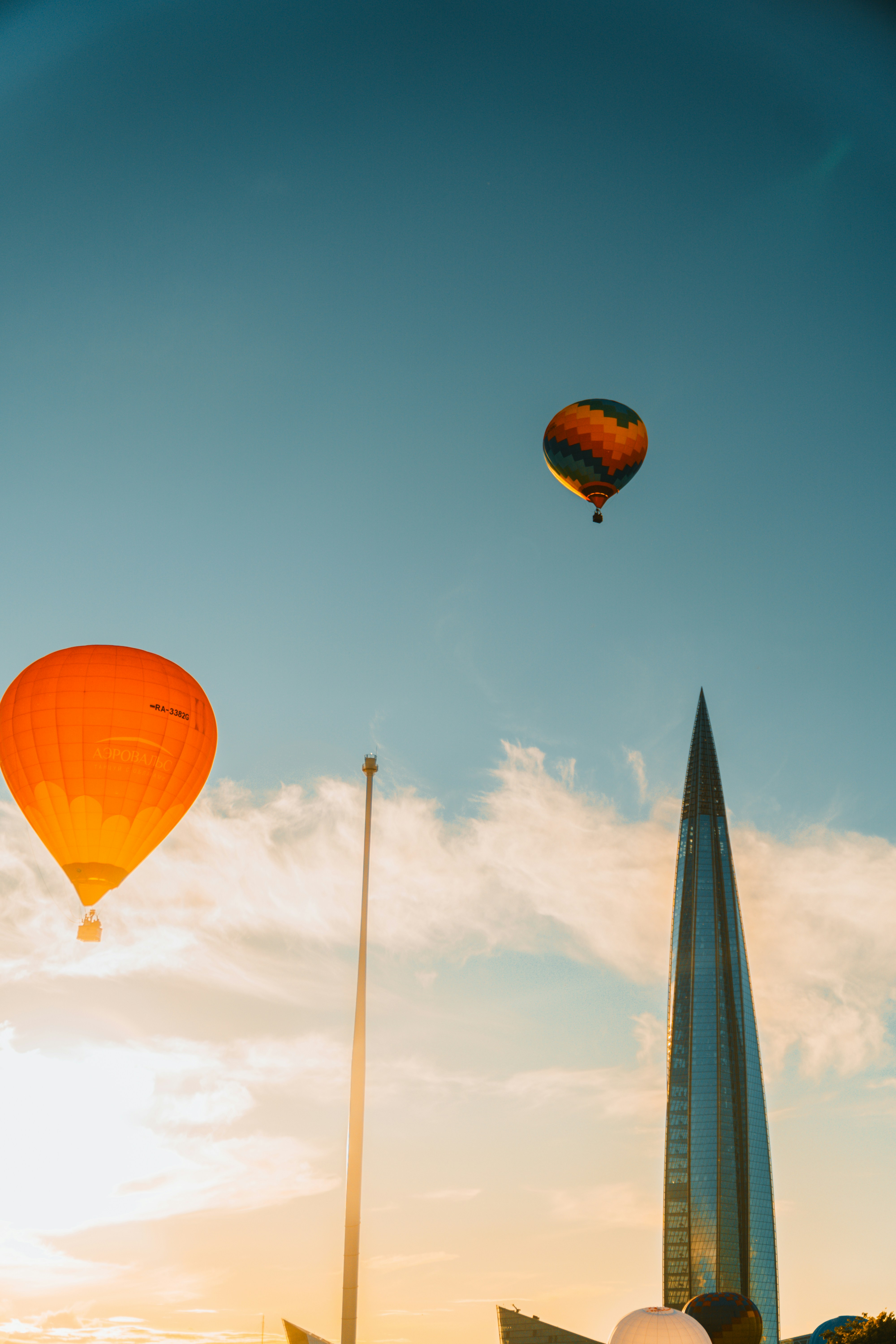 Les montgolfières volent près d’un gratte-ciel moderne au coucher du soleil.