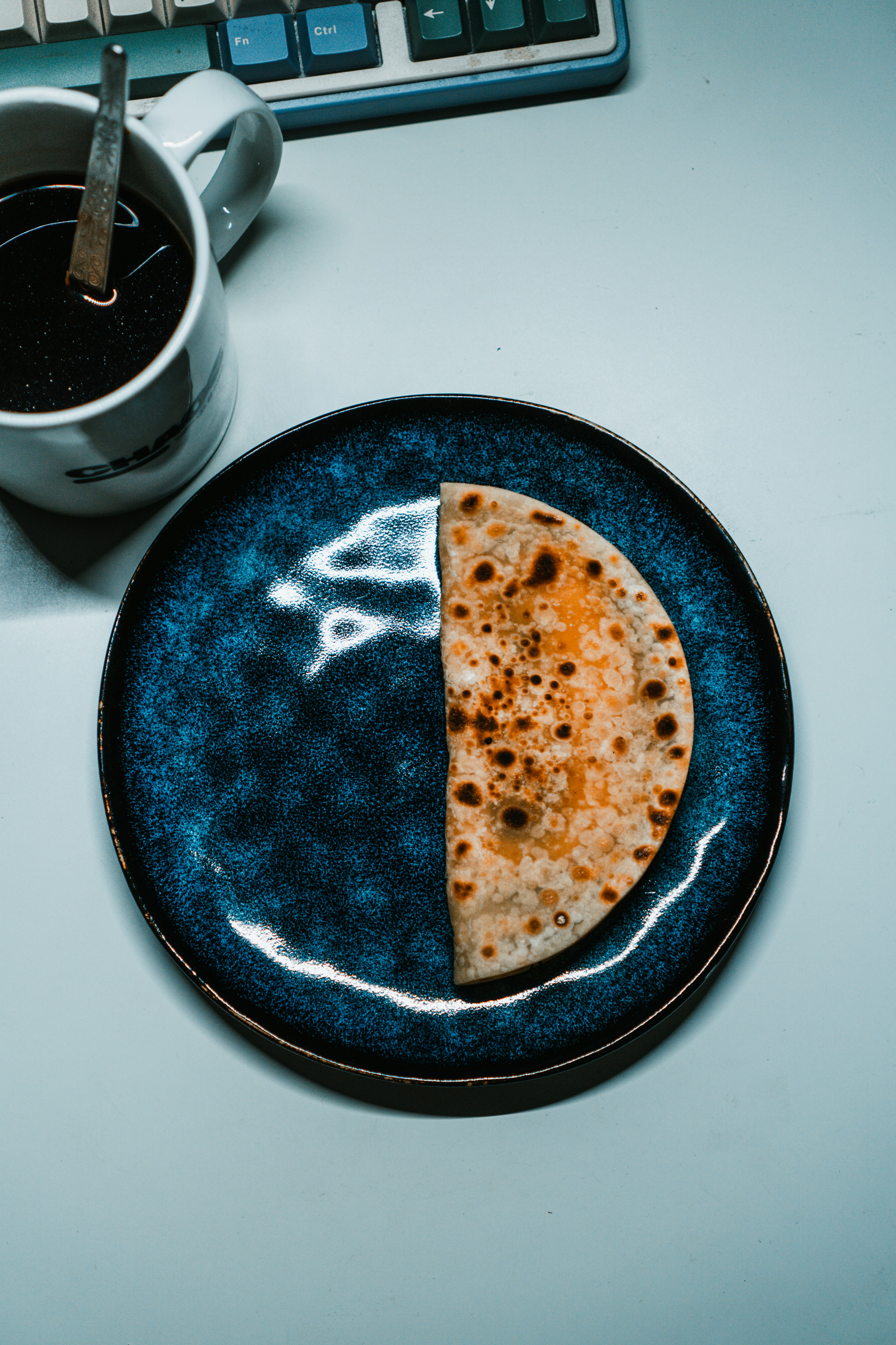 Half a flatbread on a blue plate with coffee.