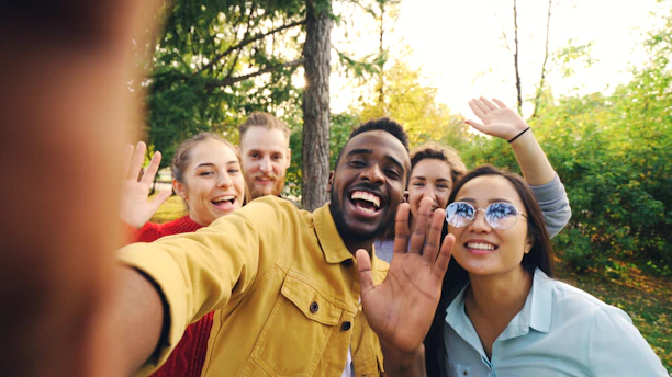 Group of friends waving and smiling outdoors
