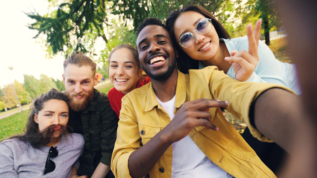 A diverse group of friends taking a selfie in the park