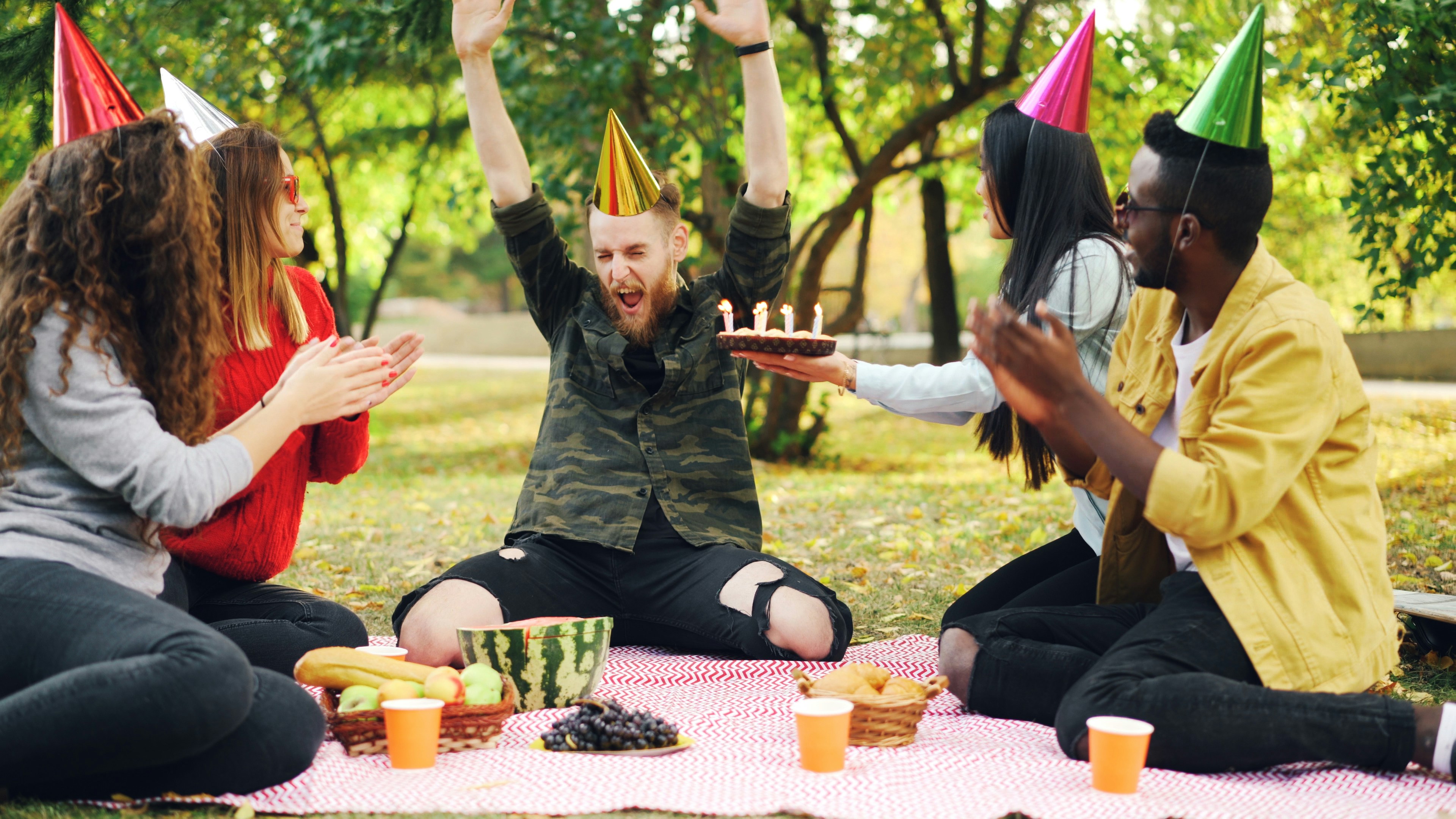 Friends celebrating a birthday with cake in park