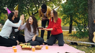 Friends celebrating birthday outdoors with cake and party hats