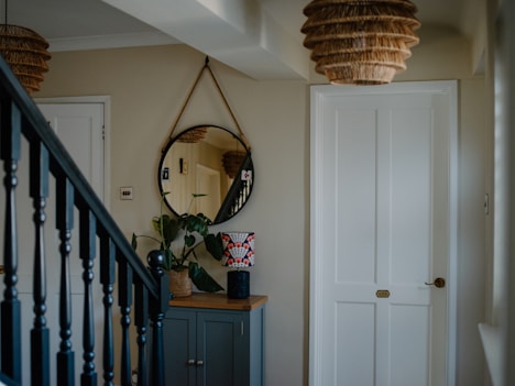 Hallway with staircase, mirror, and cabinet.