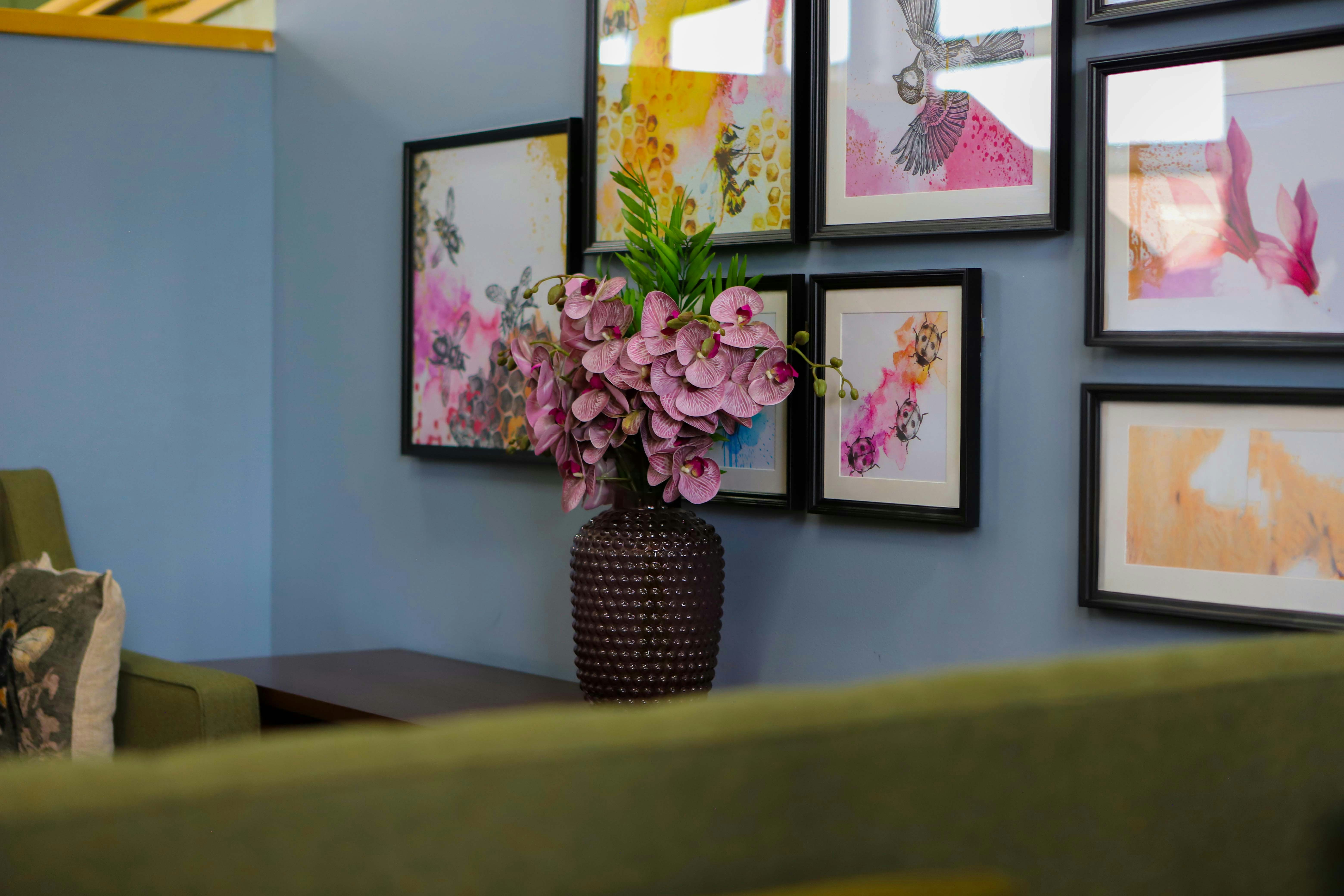 Pink flowers in vase on table with artwork