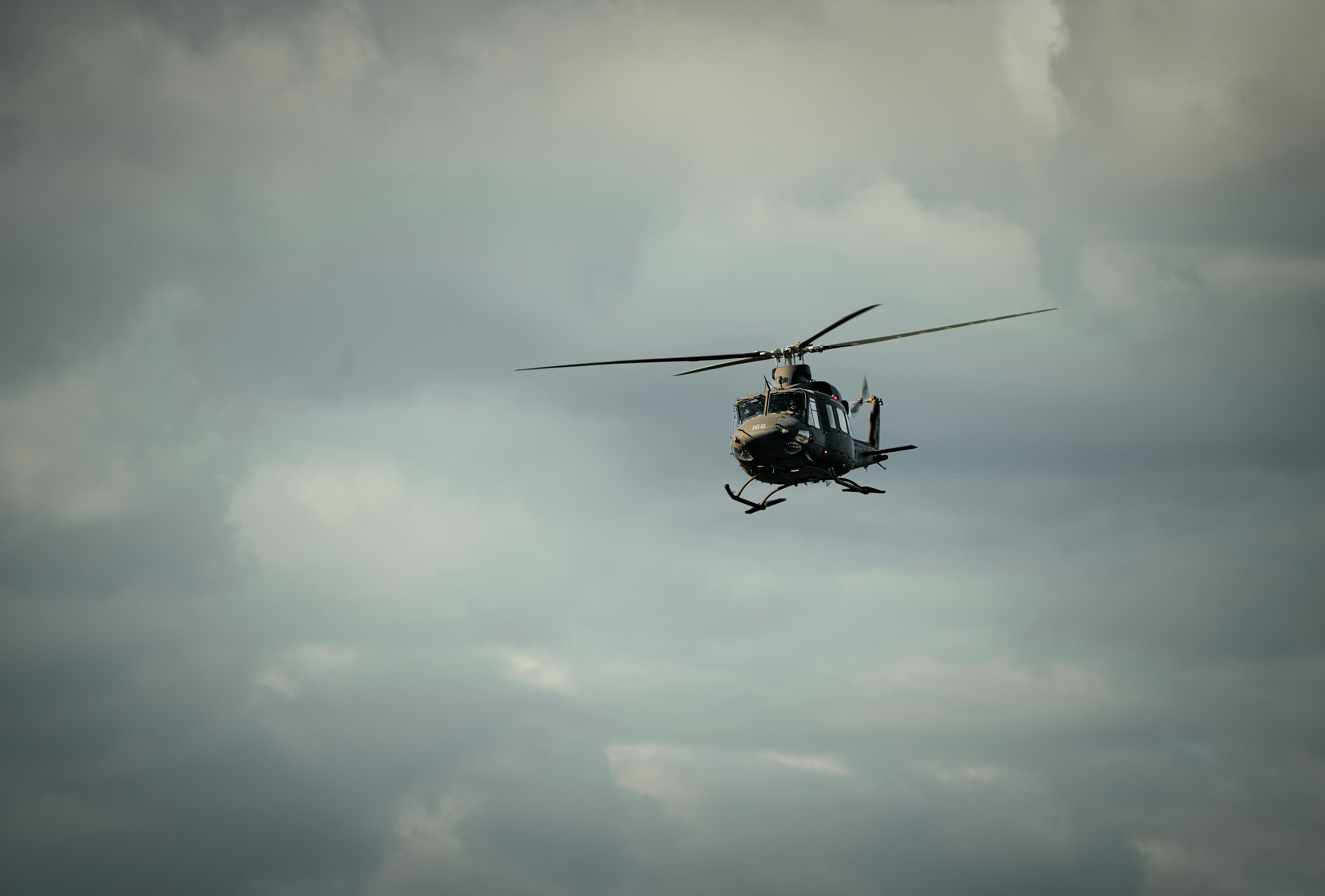 A helicopter flies through a cloudy sky