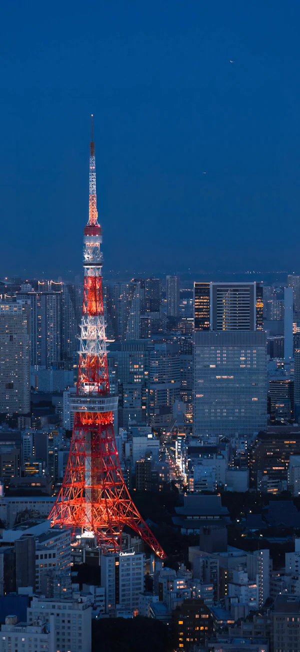 Tokyo Tower lit up at dusk among the city lights of Tokyo