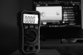Digital multimeter displays zero in front of computer screen