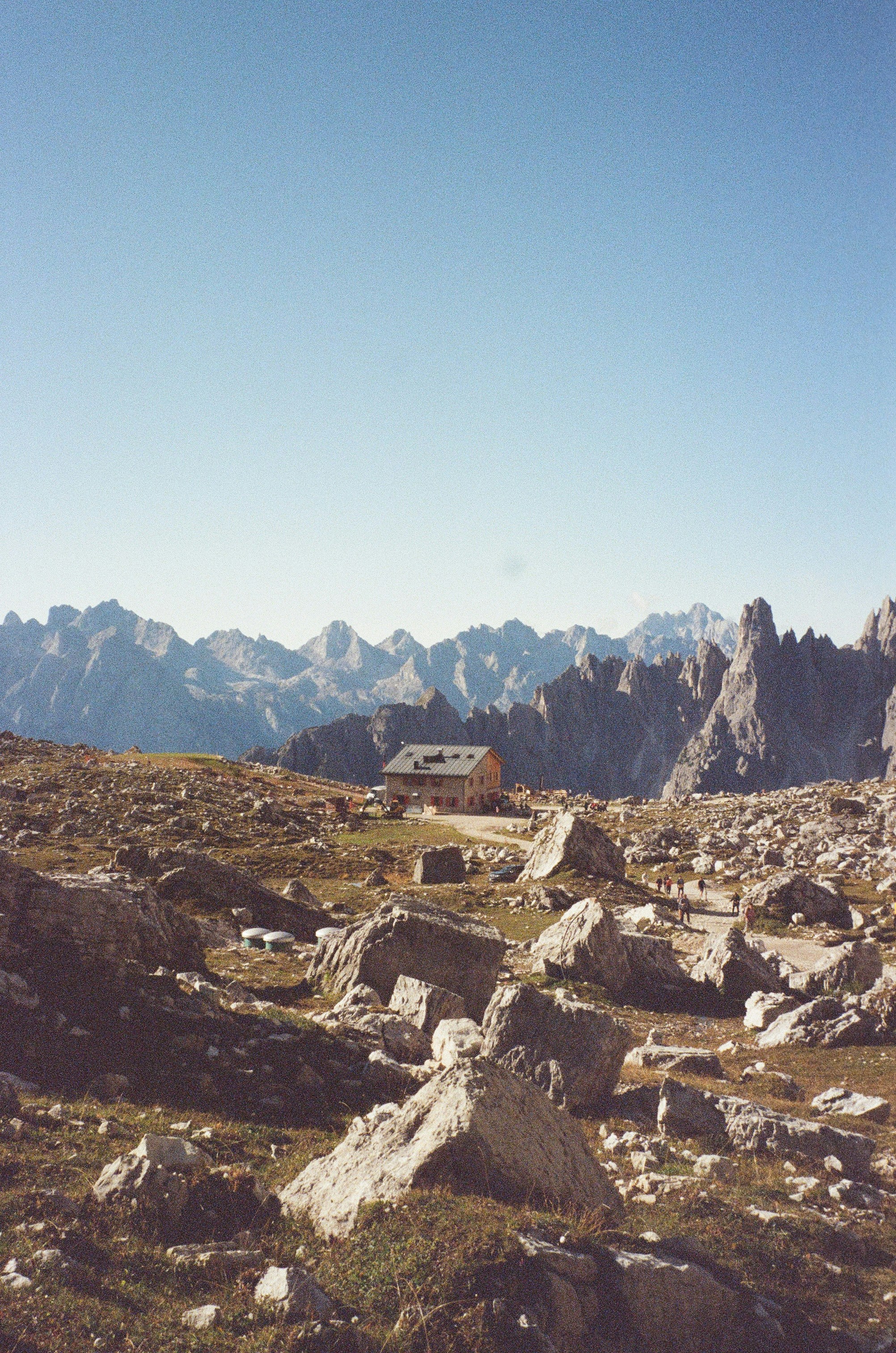 Mountain hut amidst rocky terrain with distant peaks.
