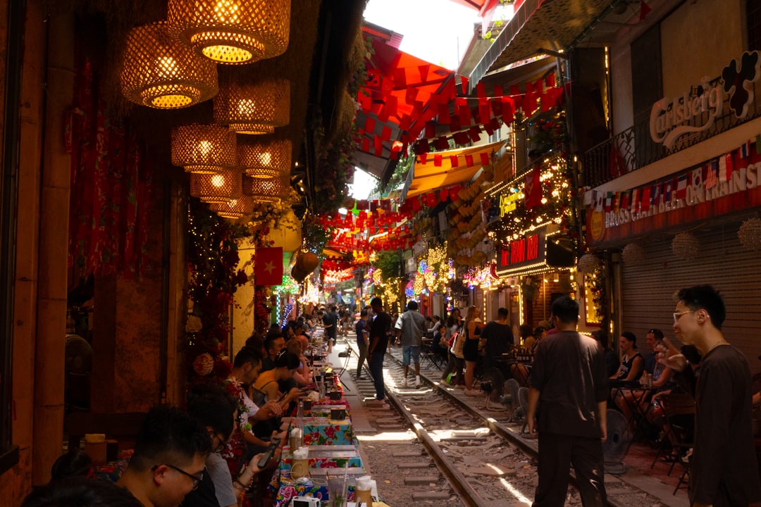 Busy street with people dining near train tracks.