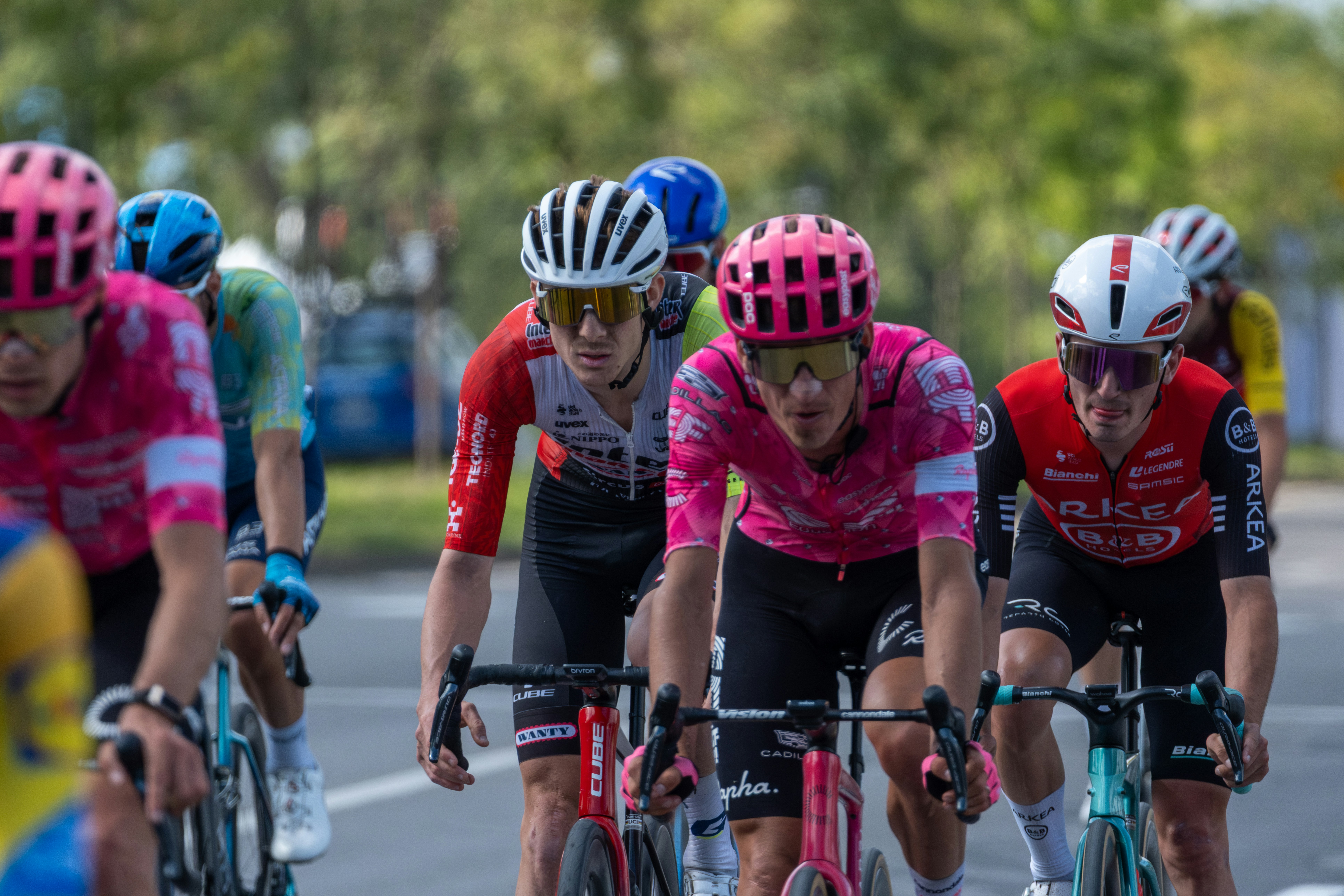 Cyclists in a race wearing colorful jerseys and helmets.