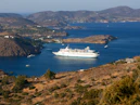 A large white cruise ship anchored in a blue bay