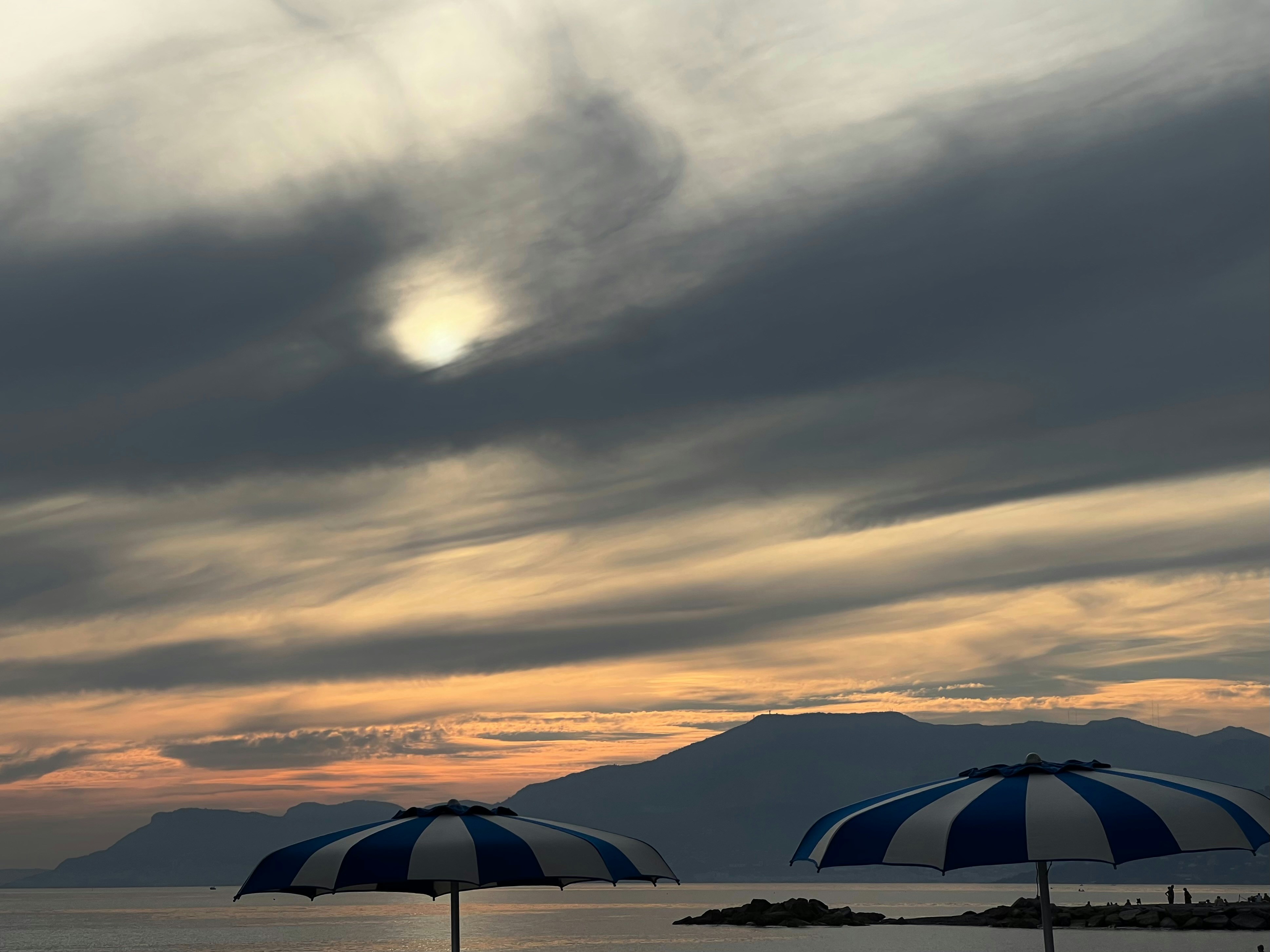 Sonnenschirme vor einem bewölkten Sonnenuntergangshimmel