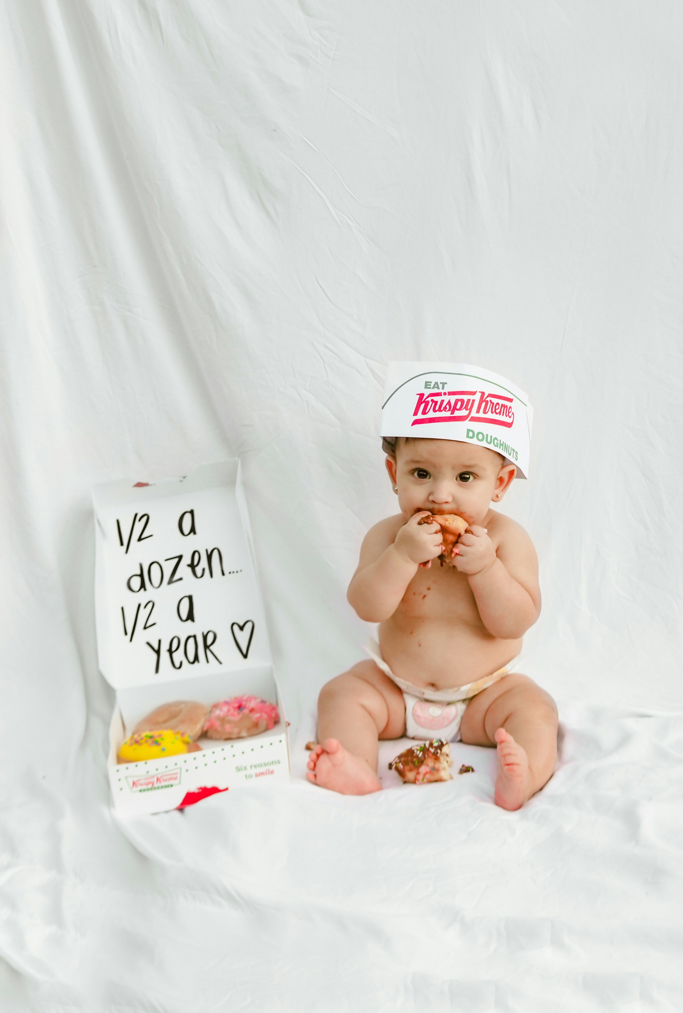 Baby eating donut with half dozen donuts box