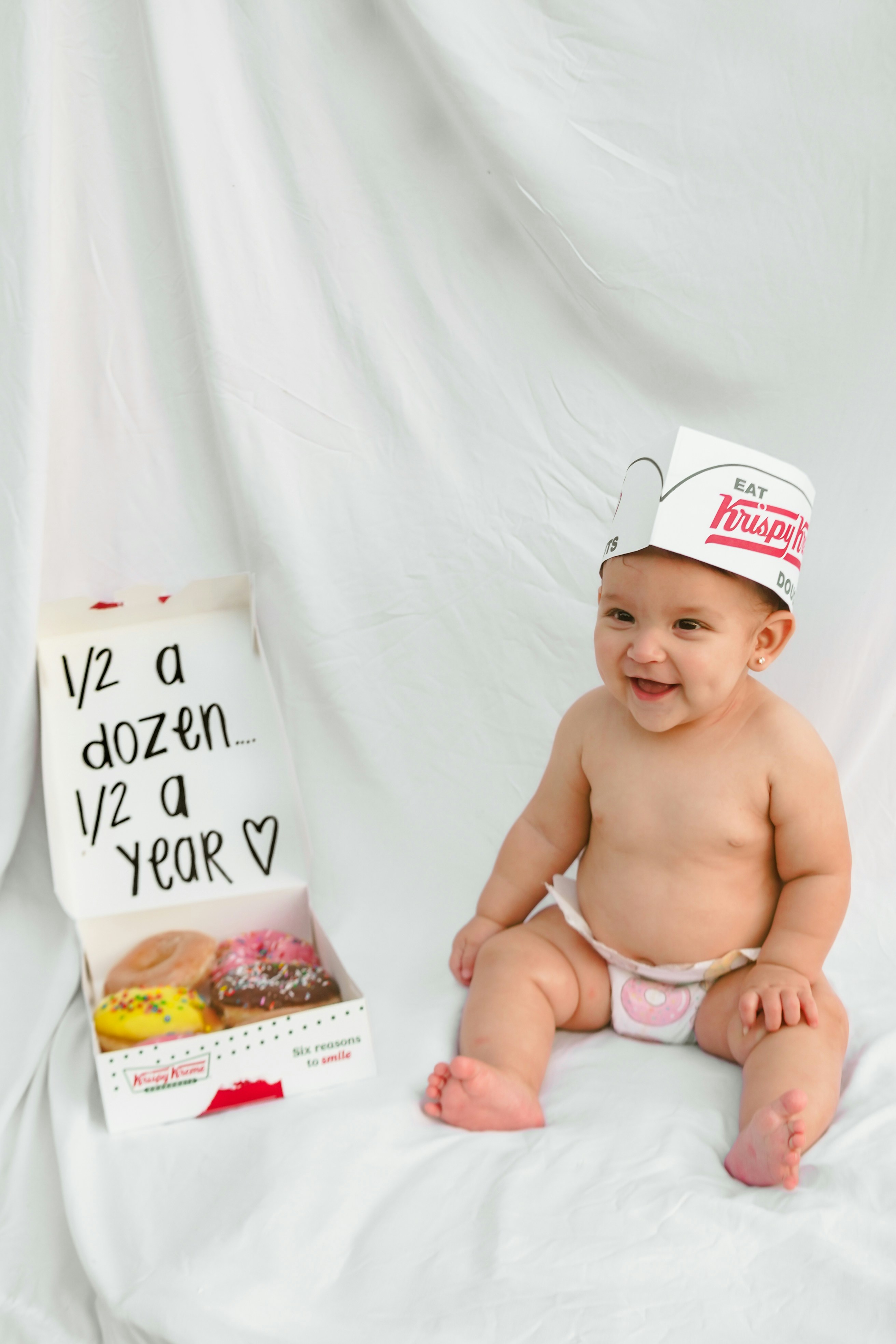 Baby wearing a donut hat with a donut box