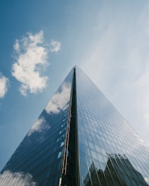 Modern glass skyscraper reflecting blue sky and clouds