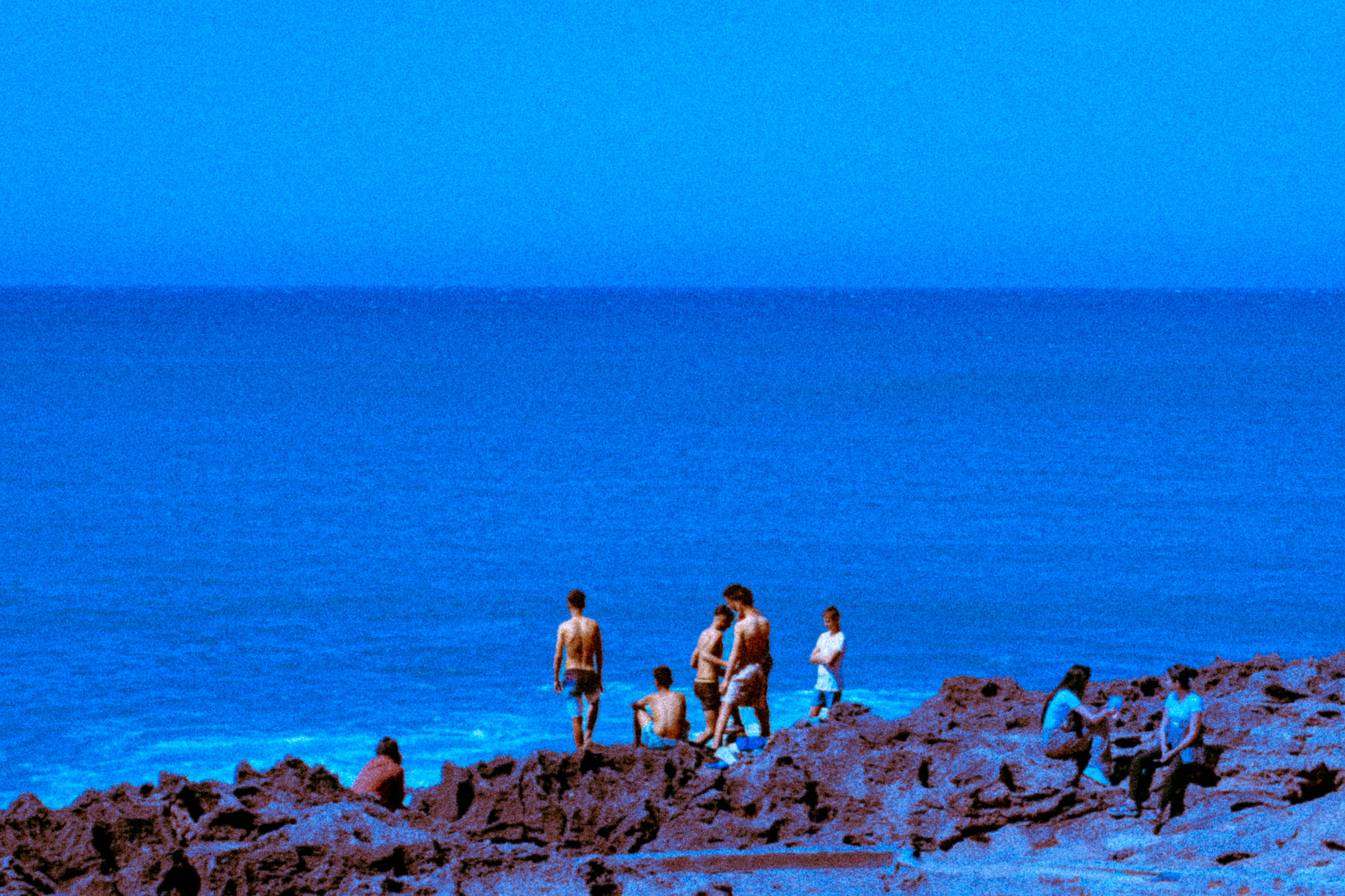 La gente se reunió en la costa rocosa junto al océano azul