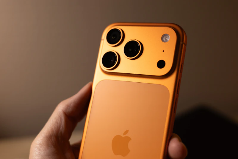 An iPhone 17 Pro in Cosmic Orange held up to show the camera array
