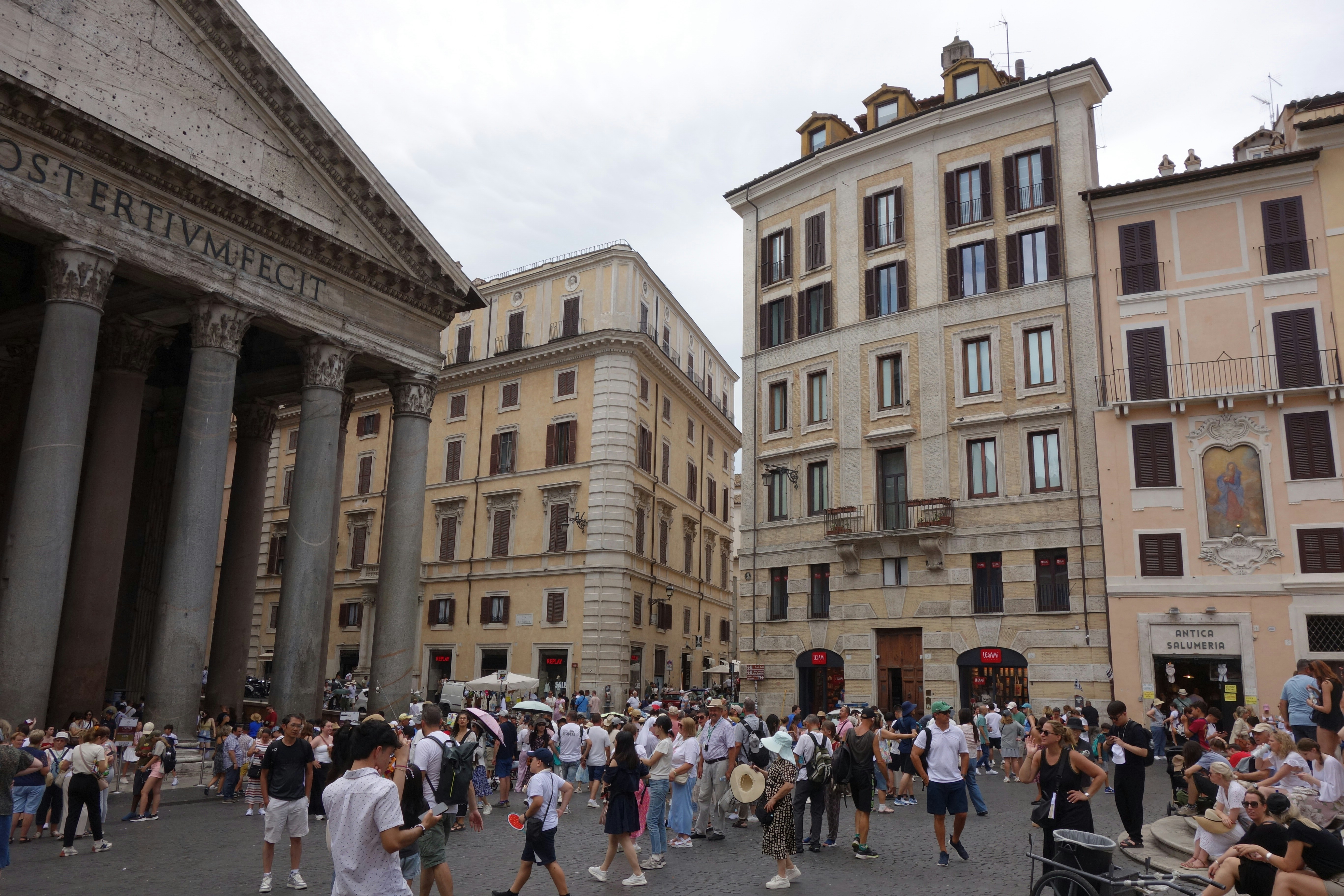 People gather in a european city square with historic buildings.