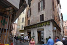 People walk past a cafe on a narrow street.