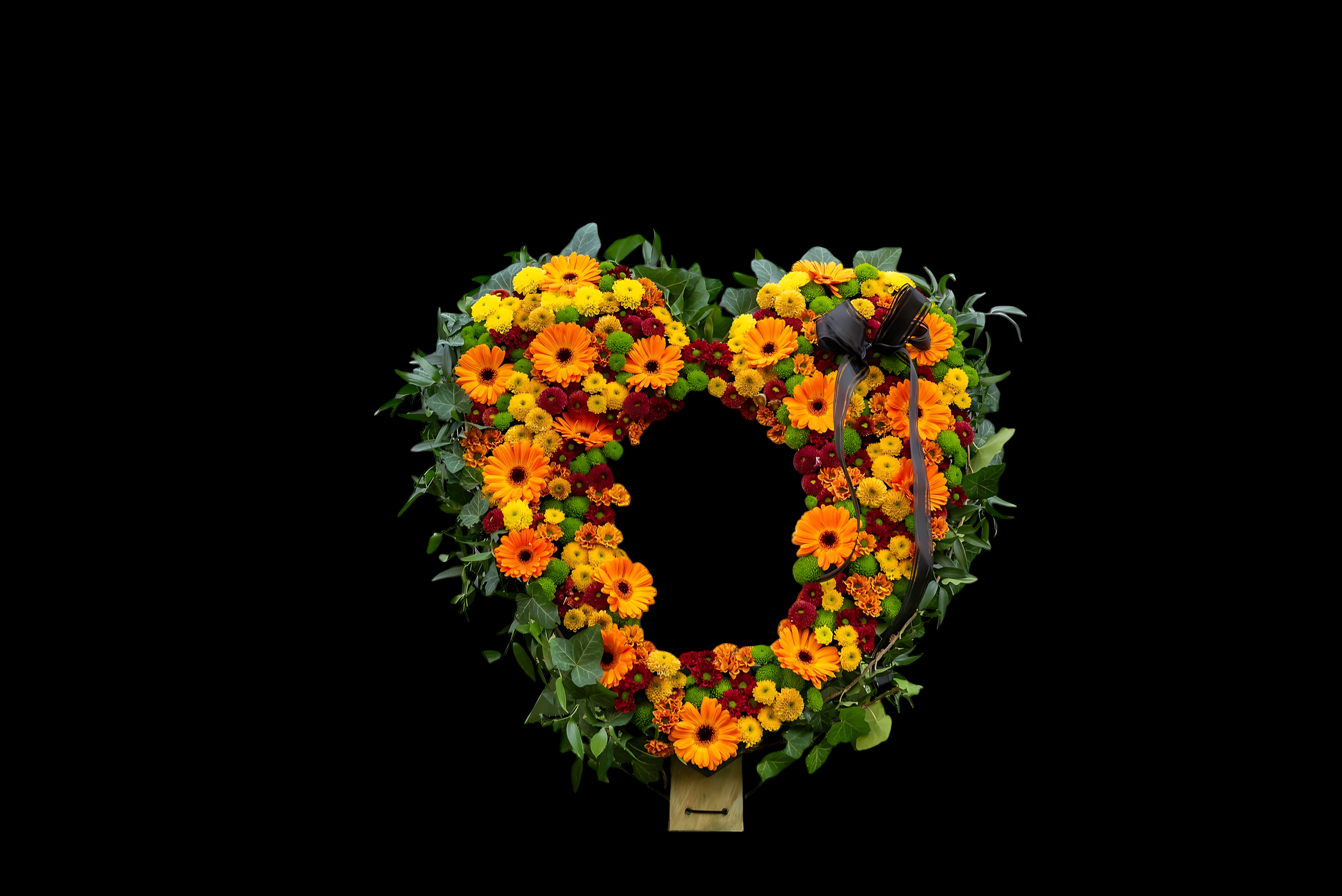 A heart-shaped wreath of orange and yellow flowers.