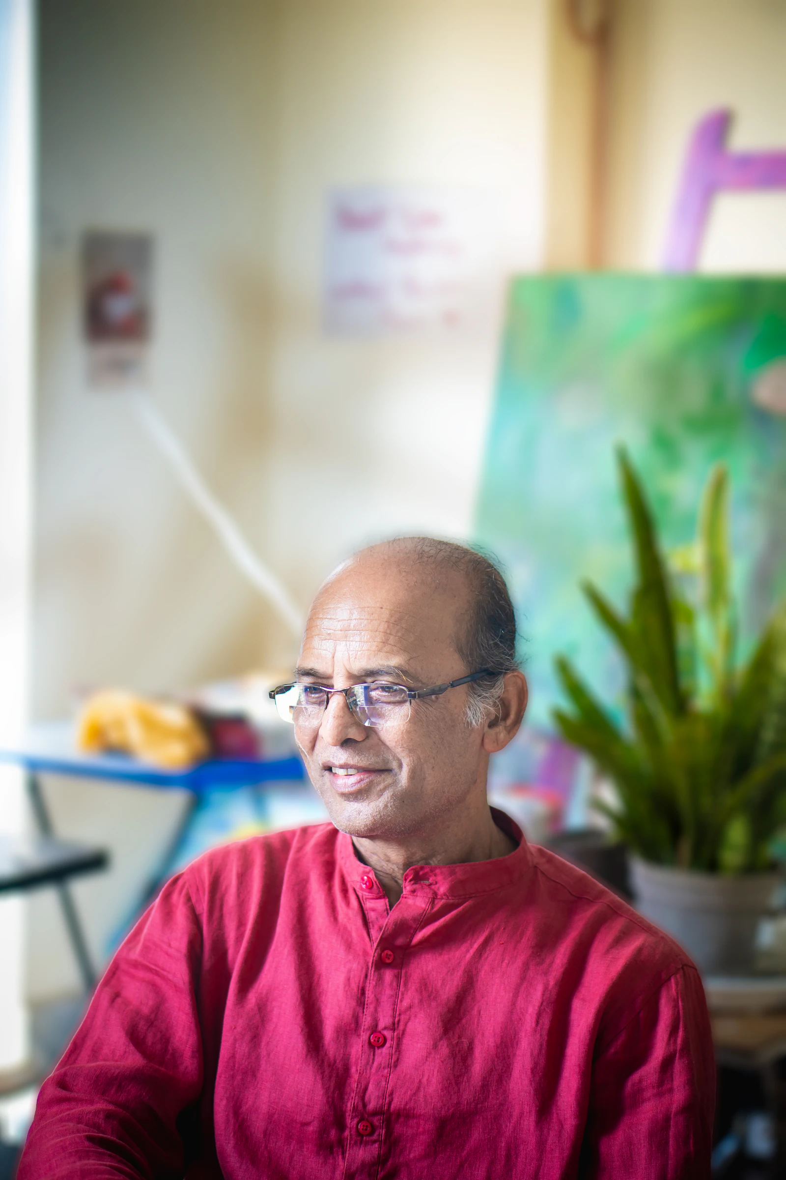 A smiling older man with glasses in a red shirt