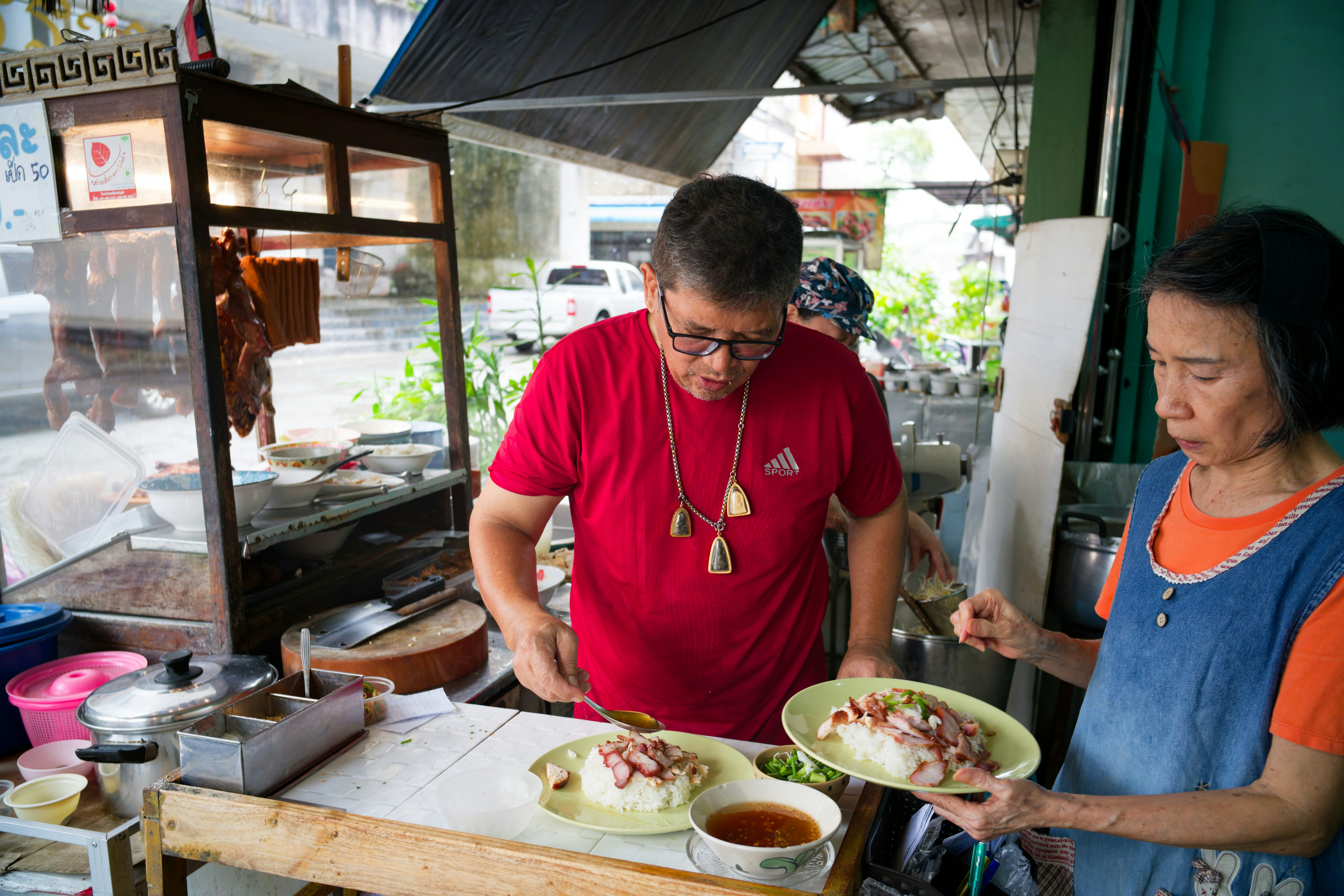 Two people preparing food at a street food stall