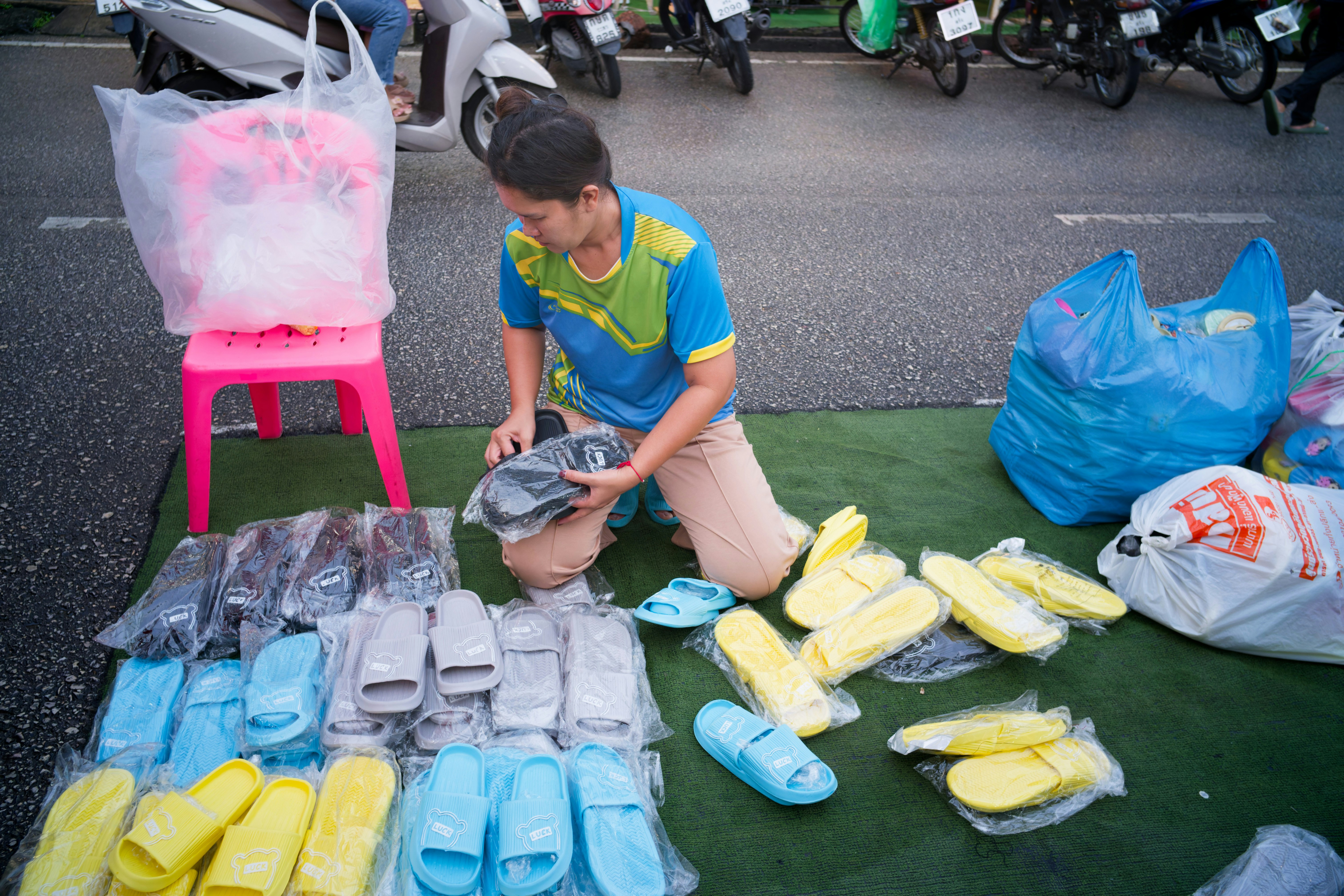 Vendor arranging sandals and slippers at a street market
