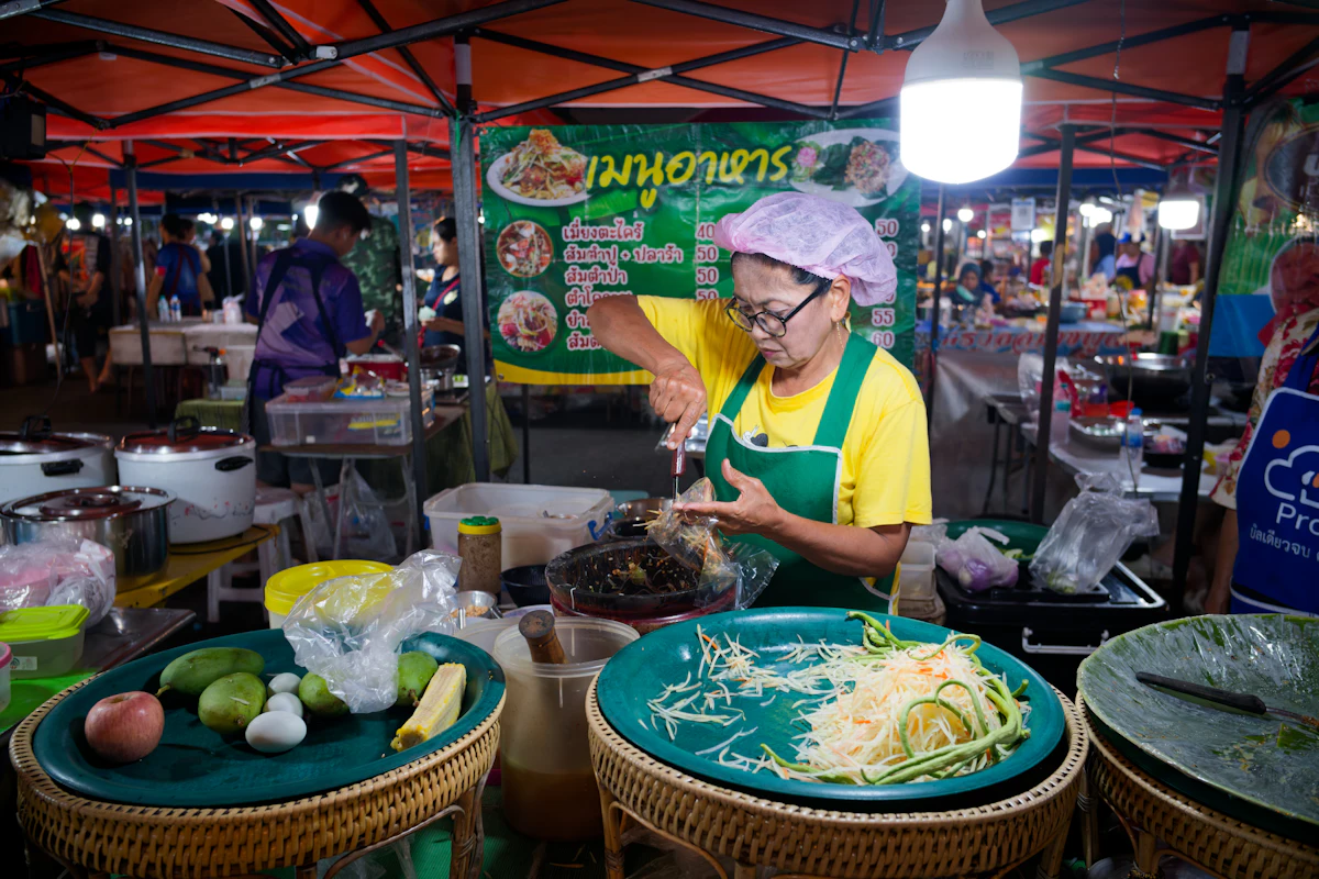 Vendedora preparando comida en un puesto de un mercado nocturno tailandés