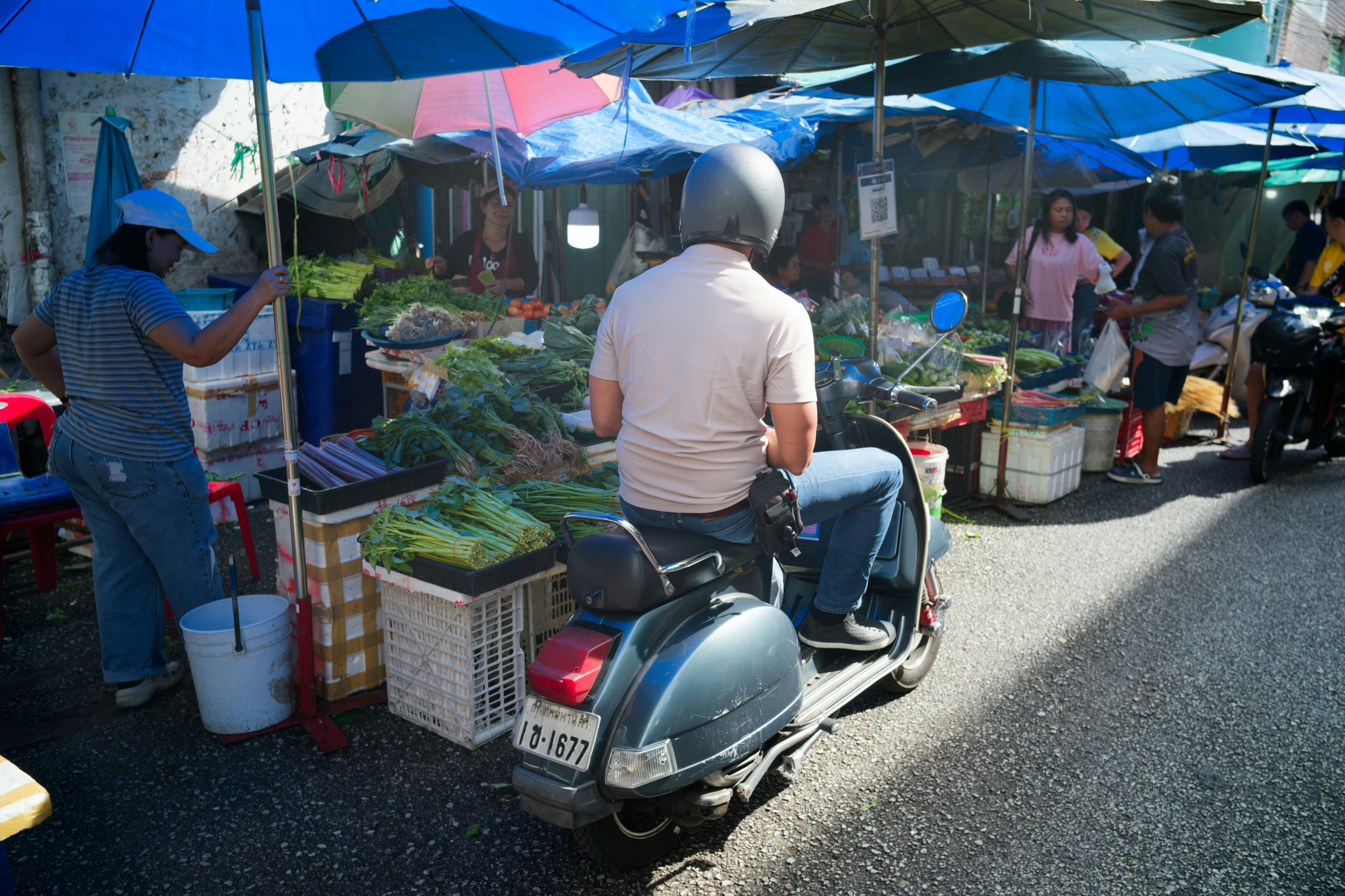 にぎやかな屋外市場でスクーターに乗った男。