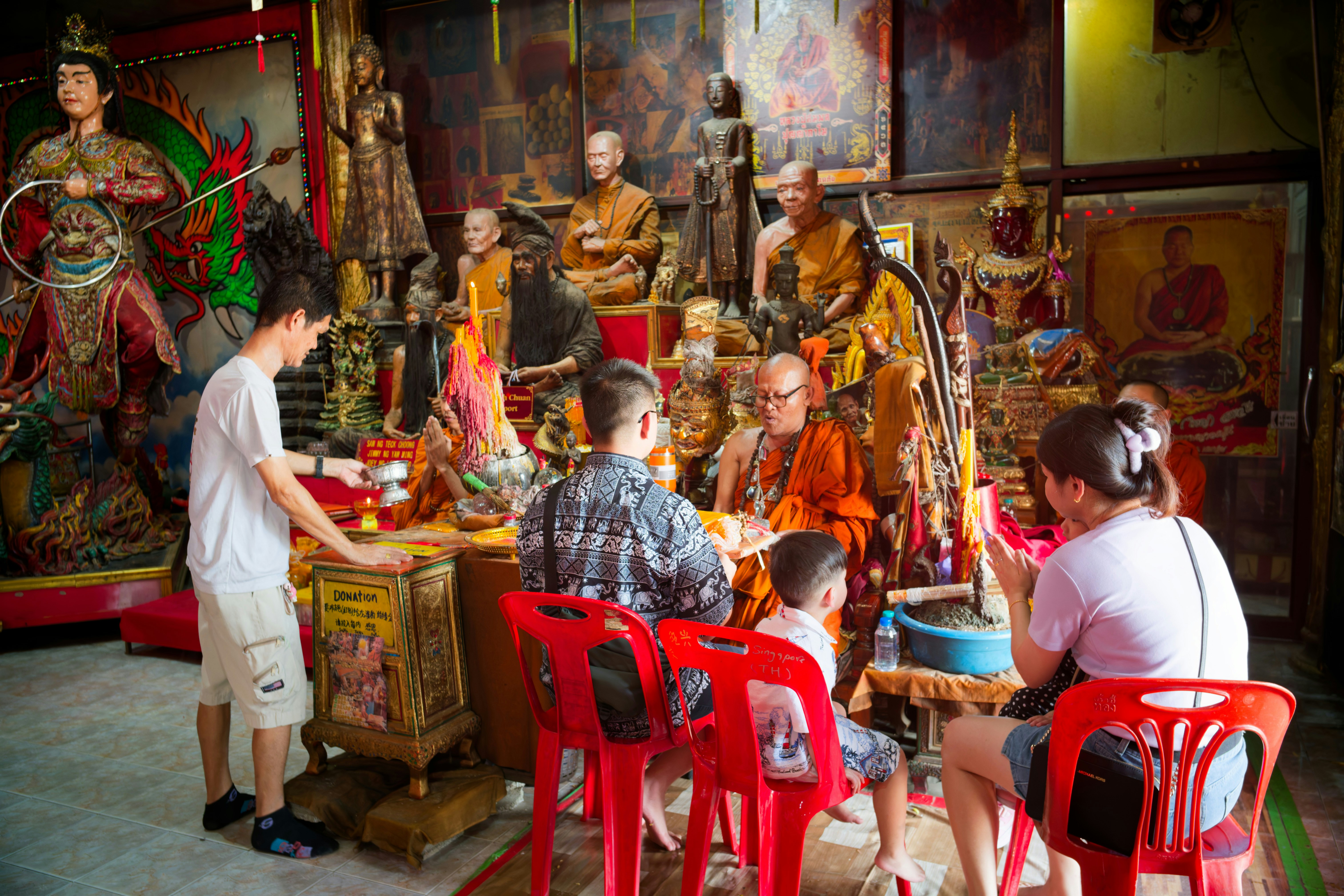 People gathered in a shrine with statues and offerings.