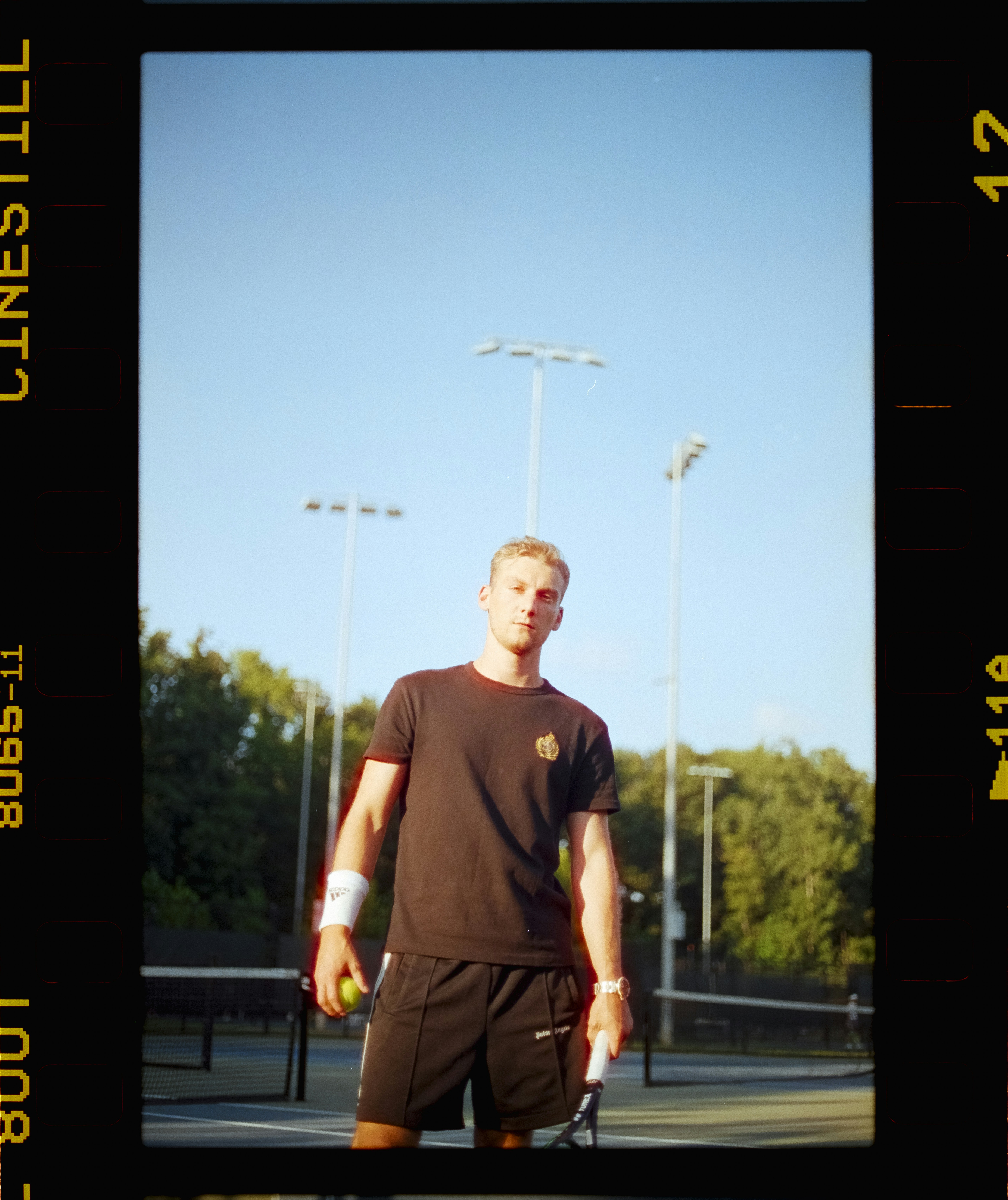 Junger Mann hält Tennisschläger und Ball auf dem Platz.