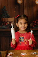 Girl holding rolling pin and honey dipper with cookies