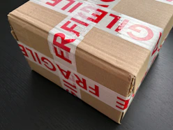 Cardboard box sealed with red fragile tape