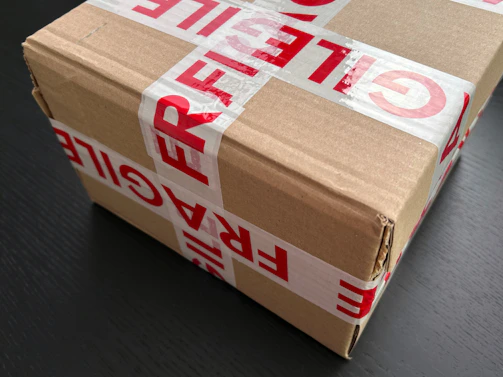 Cardboard box sealed with red fragile tape