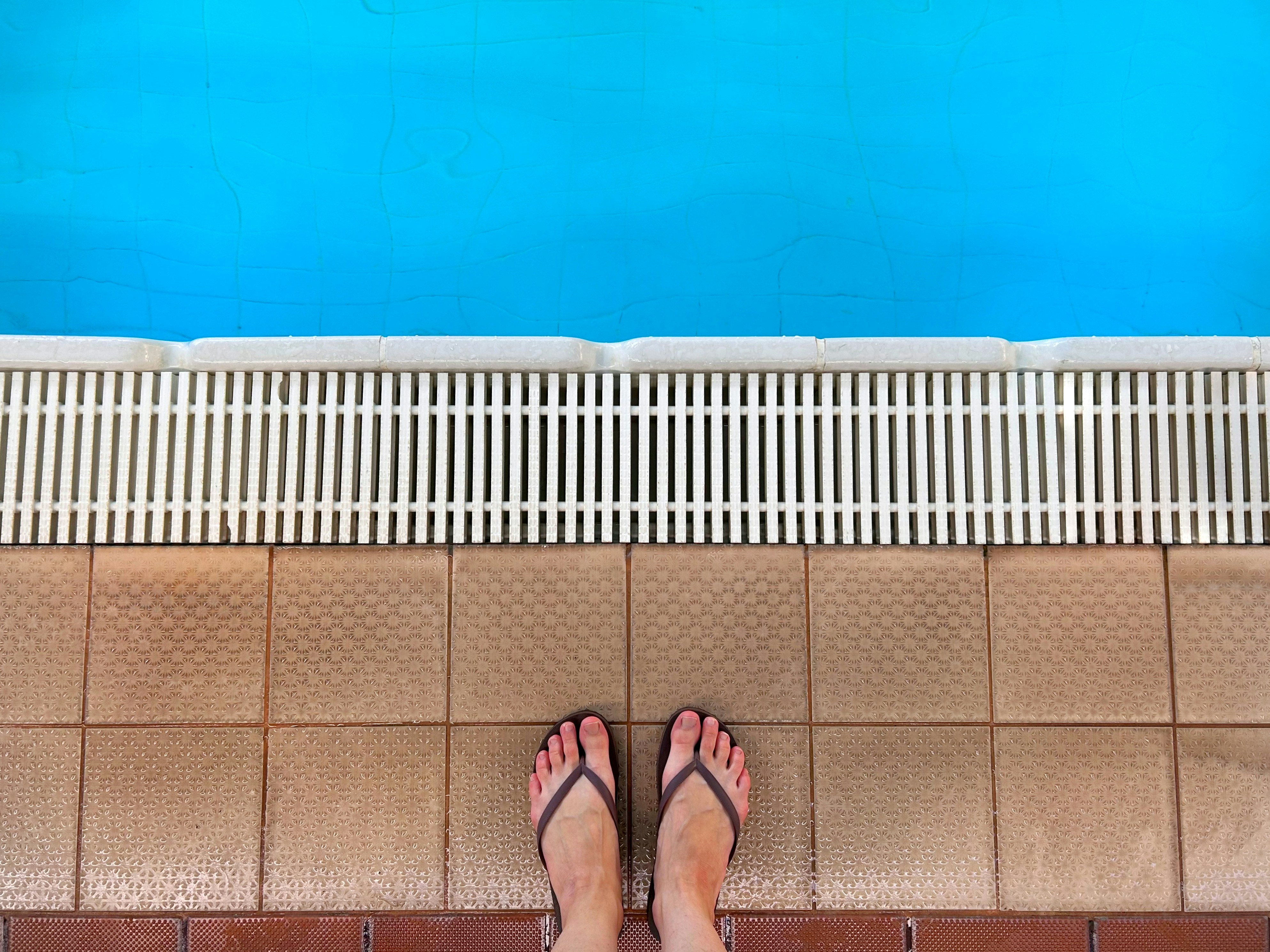 Feet in flip-flops by a swimming pool
