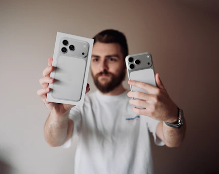 Man holding an iPhone and its box