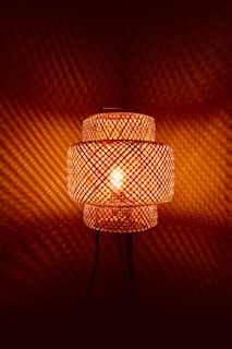 Woven bamboo lamp casting patterned light on wall